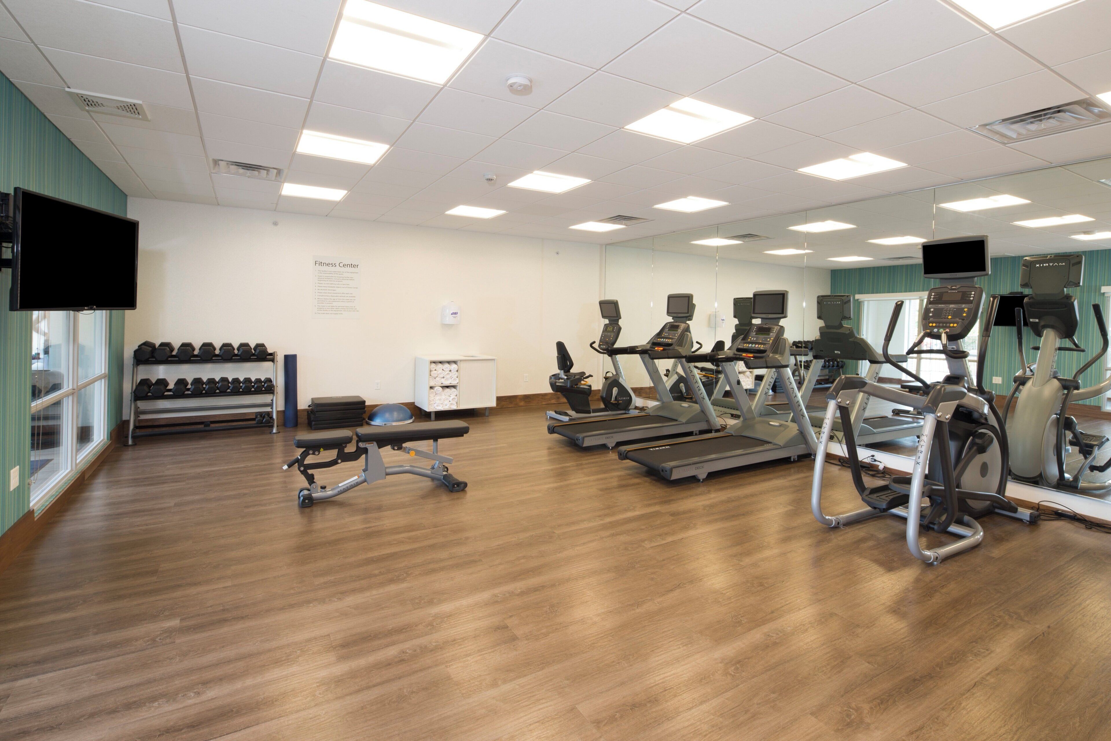 A fitness center with treadmills, elliptical machines, and dumbbells.