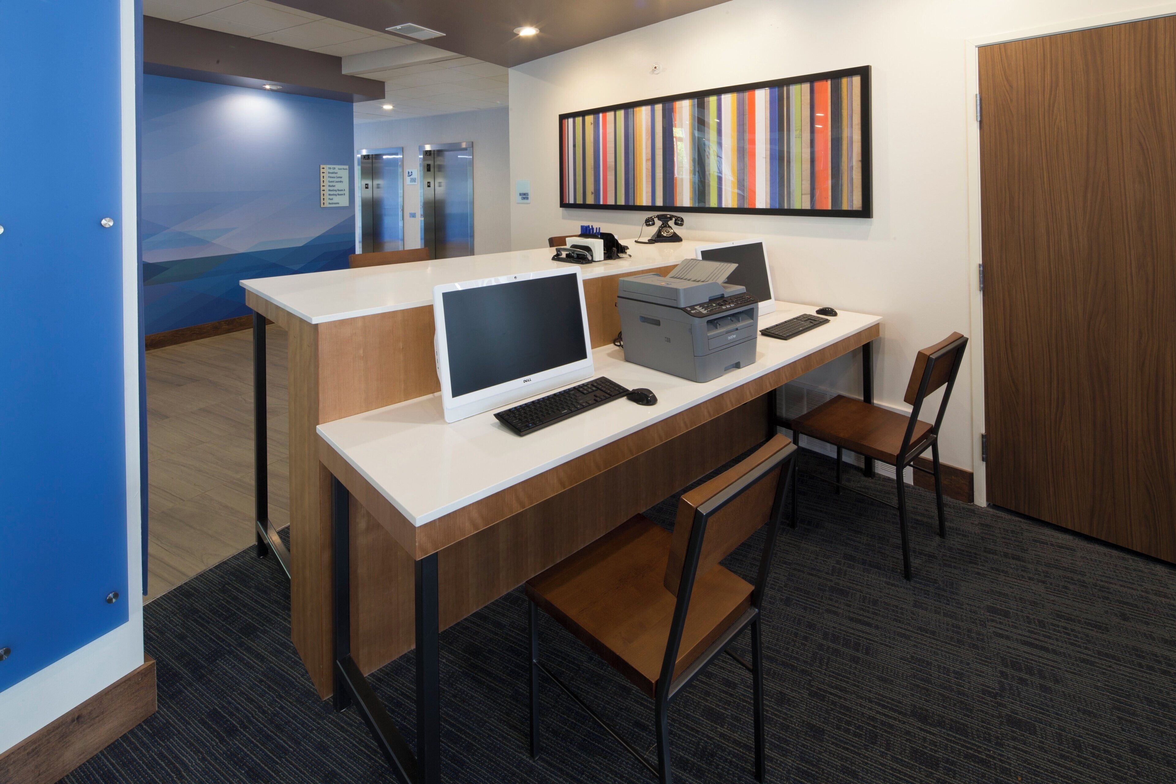 A modern office space with a desk, computer, printer, and a telephone.