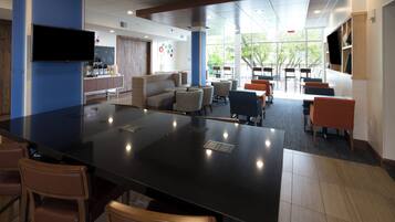 A modern indoor space with a central bar area, seating arrangements, and a television mounted on the wall.