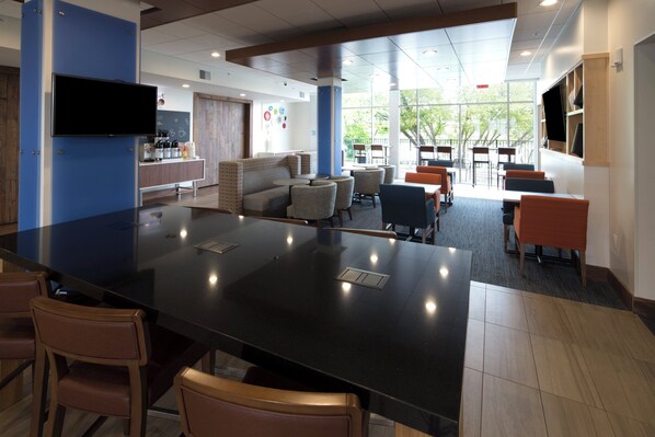 A modern indoor space with a central bar area, seating arrangements, and a television mounted on the wall. - Holiday Inn Express & Suites Alpena - Downtown by IHG (Alpena)