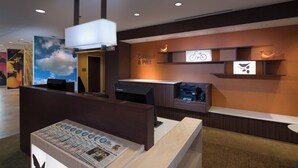 A reception desk with a mounted computer, a wall-mounted printer, and a bulletin board displaying a newspaper. - Fairfield Inn & Suites Houma Southeast (Houma)