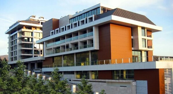 A multi-story building with a modern architectural design, featuring balconies and large windows.
