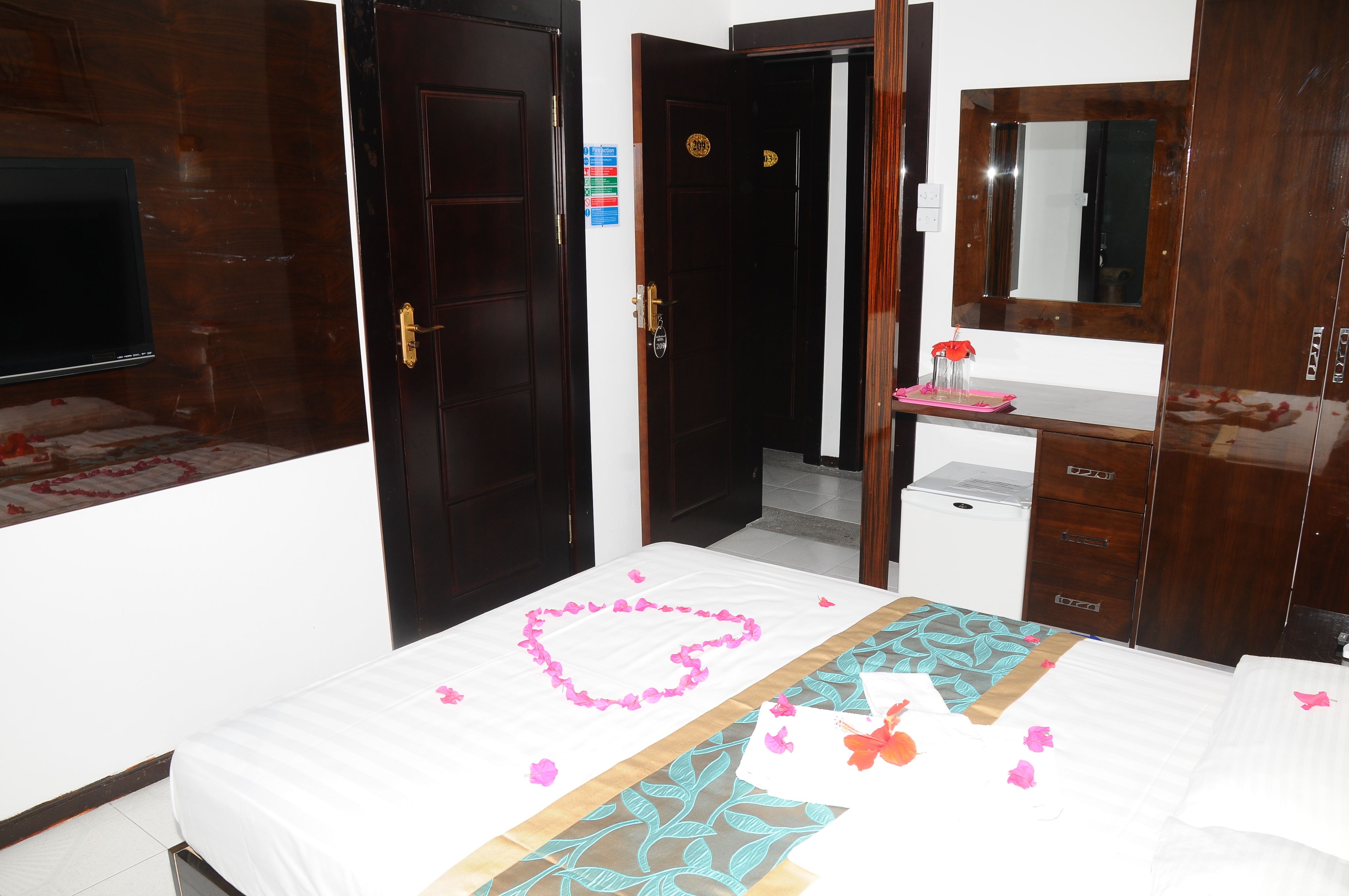 A hotel room with a bed, a dresser, a mirror, and a television.