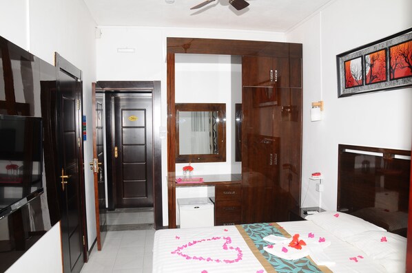 A hotel room with a bed, a desk, a wardrobe, and a mirror. - Le Flamboyant Hotel (Rodrigues Island)