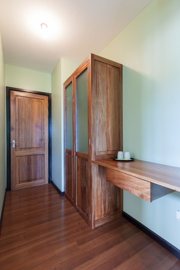 A hallway with wooden flooring and a built-in wooden cabinet with a shelf.