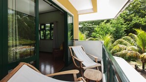 A balcony with two wooden chairs and a view of lush greenery. - Lakaz Safran (La Digue)
