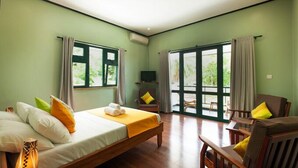 A hotel room with a bed, a TV, a chair, and a table. - Lakaz Safran (La Digue)