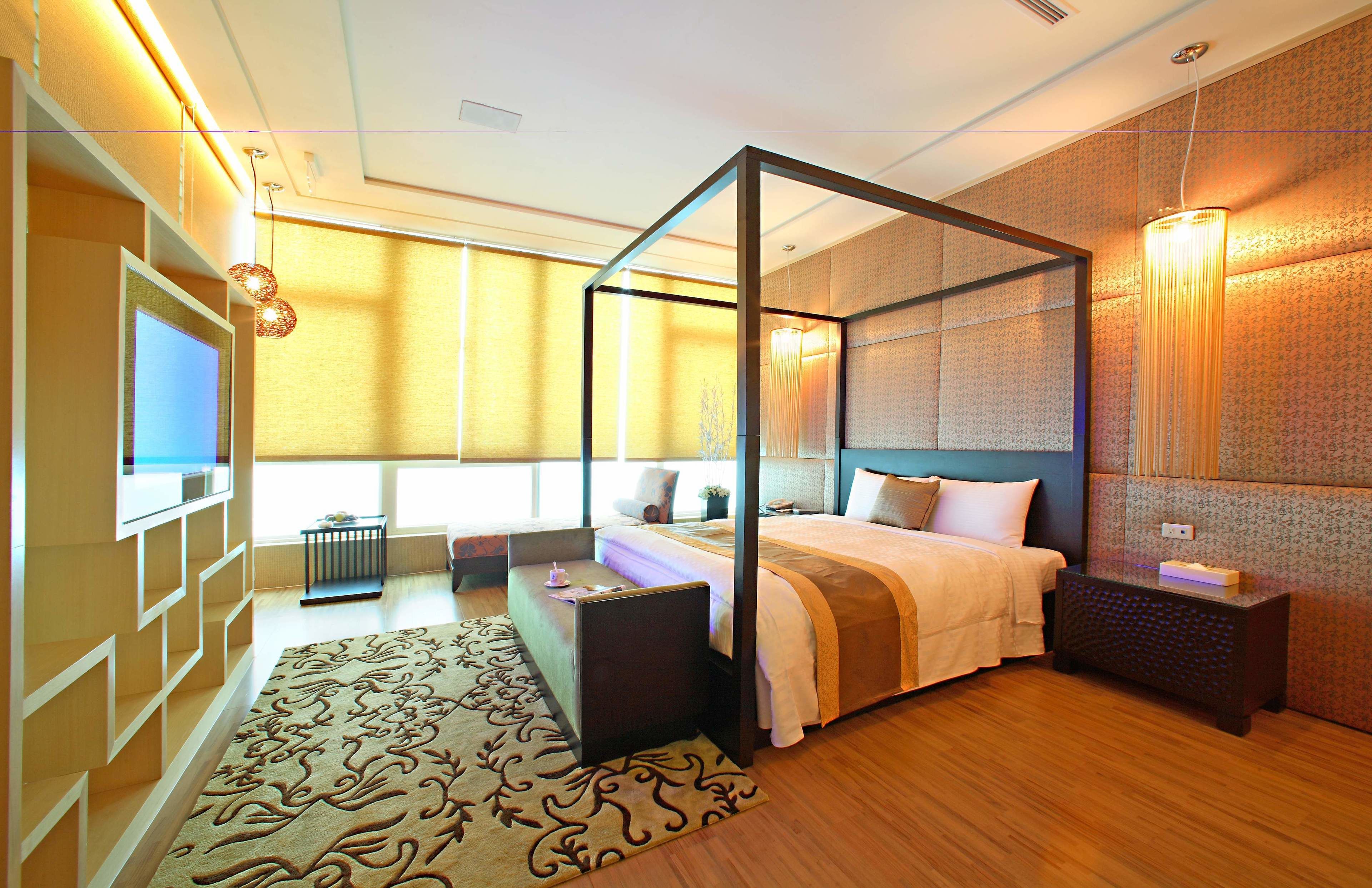 A modern bedroom with a four-poster bed, a TV, and a bedside table.