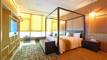 A modern bedroom with a four-poster bed, a TV, and a bedside table.