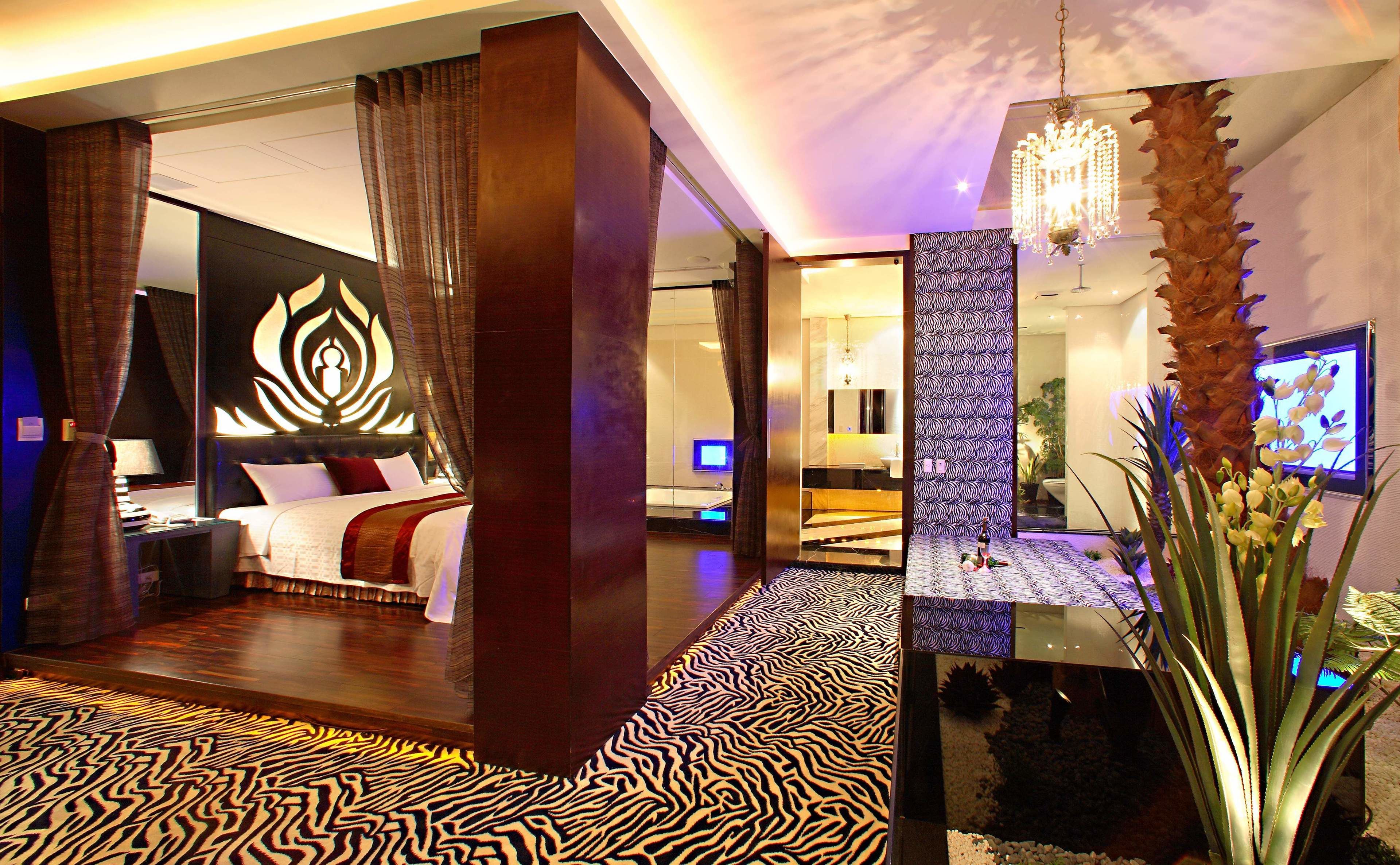 A modern hotel room with a large bed, a sitting area, and a bathroom.