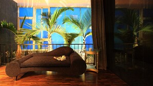 A modern living room with a curved sofa, a small side table, and a view of palm trees through large windows. - Changhua KuiKuan Boutique Motel (Changhua)