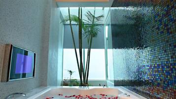 A modern bathroom with a large bathtub, a television mounted on the wall, and a decorative mosaic wall.