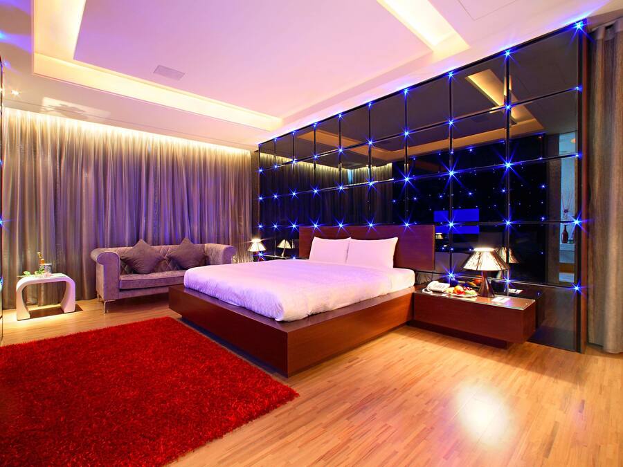 A modern bedroom with a large bed, a red rug, and a mirror wall with star lights.