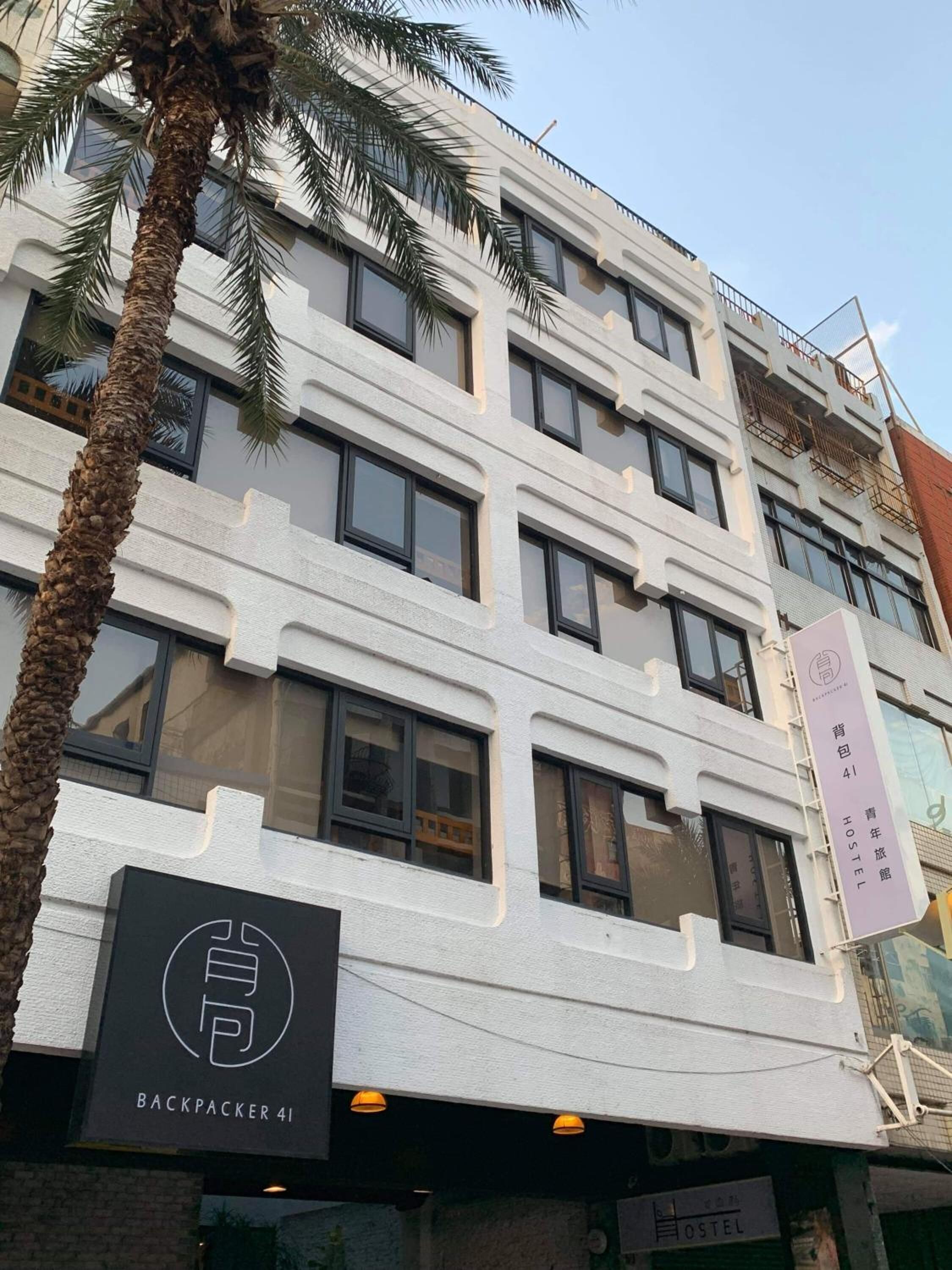 A modern building with multiple windows and balconies, featuring a sign for Backpacker 41 hostel.