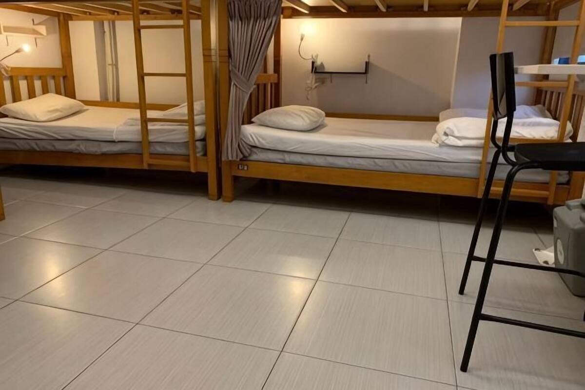 A dormitory room with bunk beds, a desk, and a chair.