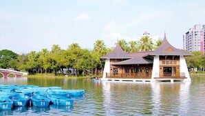 A traditional pavilion in the middle of a lake surrounded by blue boats, with a bridge in the background.