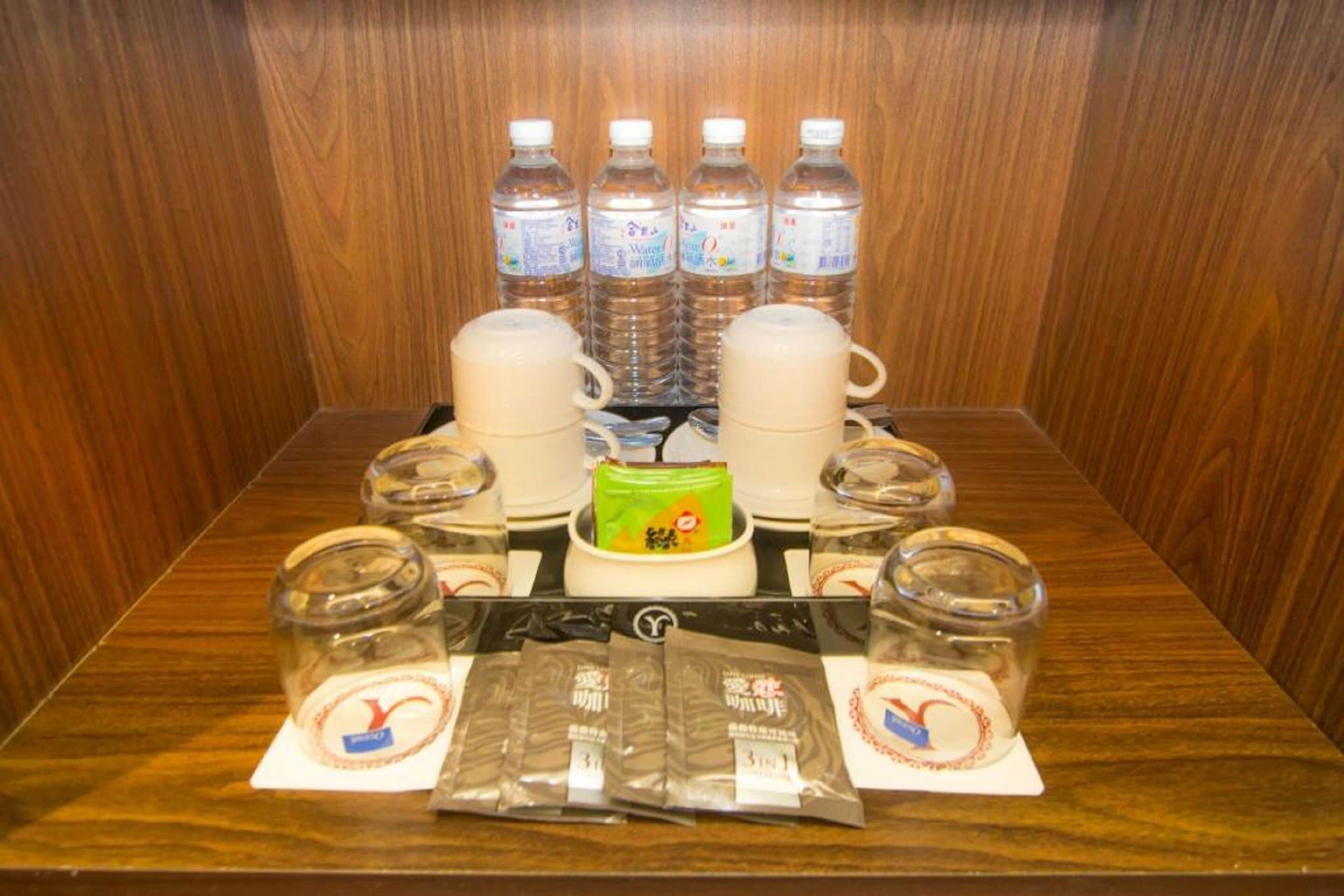 A table with water bottles, a coffee maker, and packaged snacks.