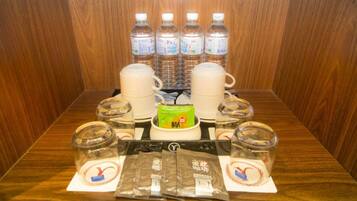 A table with water bottles, a coffee maker, and packaged snacks.
