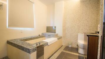 A bathroom with a granite countertop, a mirror, a toilet, and a sink.
