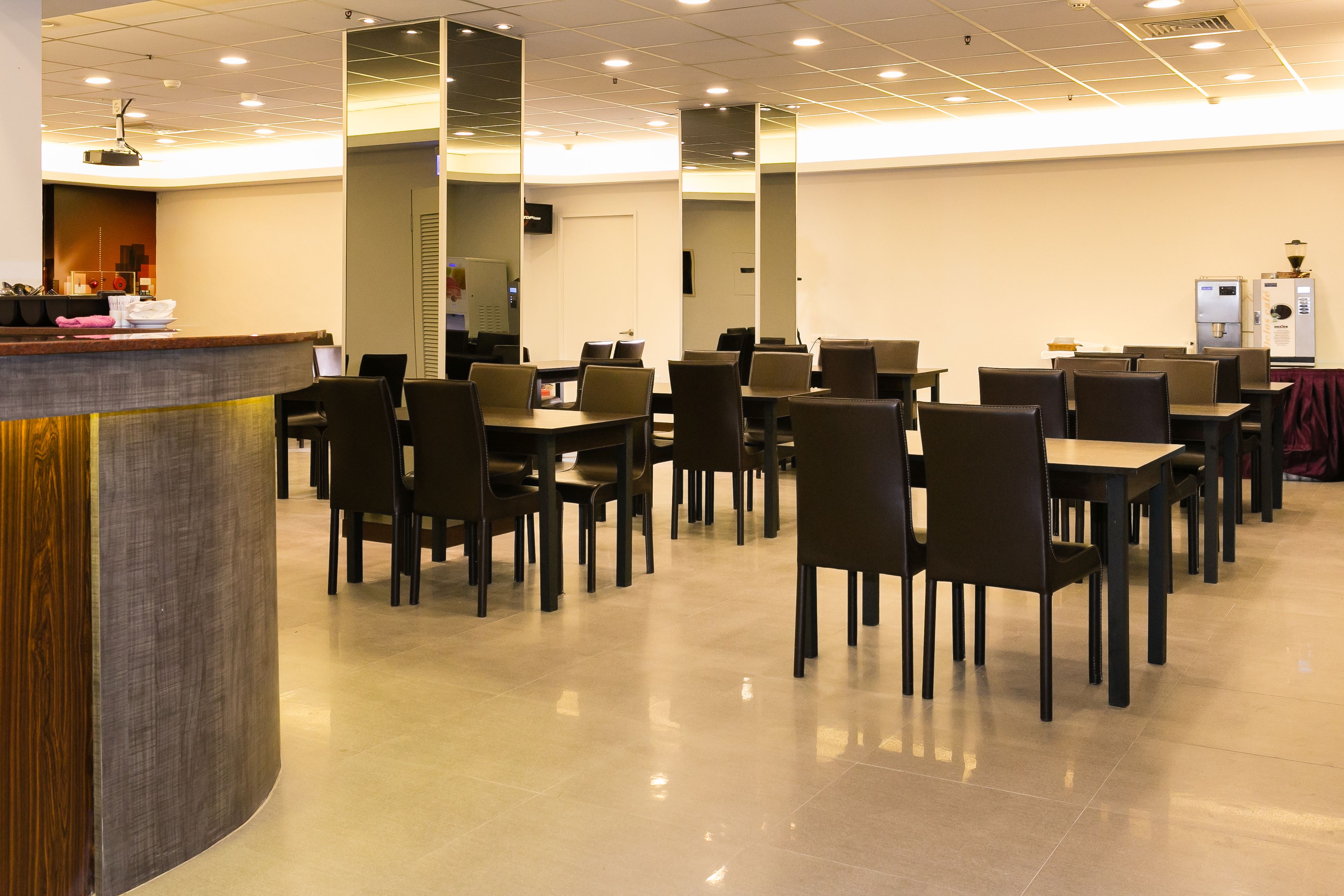 A conference room with a curved reception desk, multiple tables and chairs, and a water dispenser.