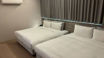 A hotel room with two beds, a ceiling-mounted air conditioner, and a headboard with built-in lighting.