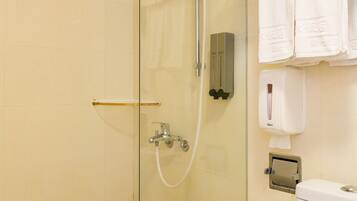 A bathroom with a glass-enclosed shower, a toilet, and a towel rack with folded towels.