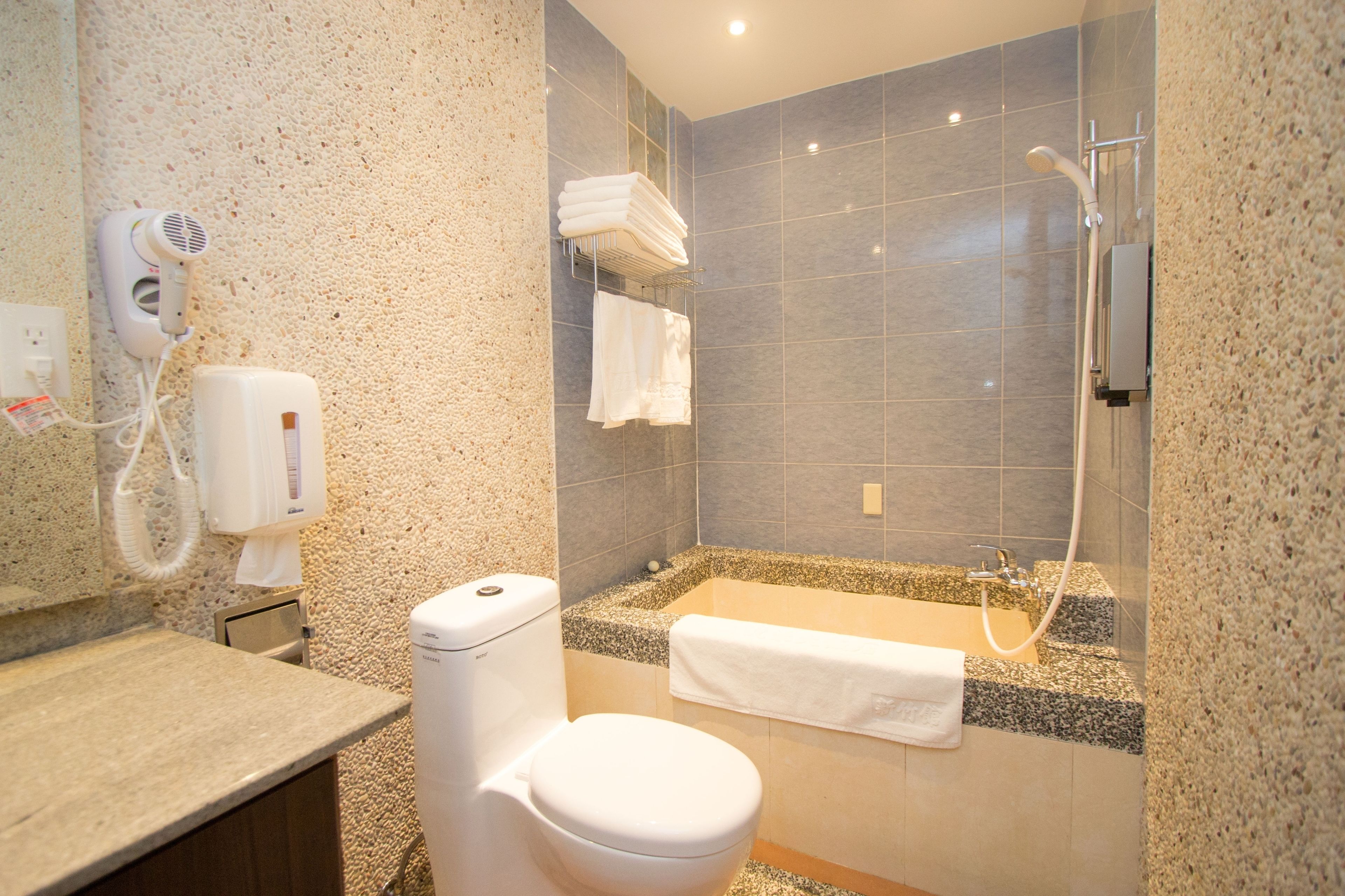 A bathroom with a toilet, a sink, a shower, and a towel rack.