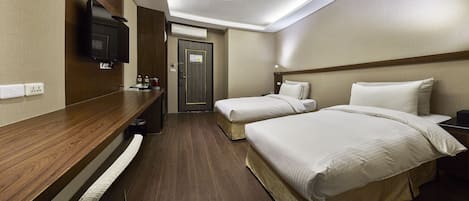 A hotel room with two beds, a wooden desk, a flat-screen TV, and a minibar.