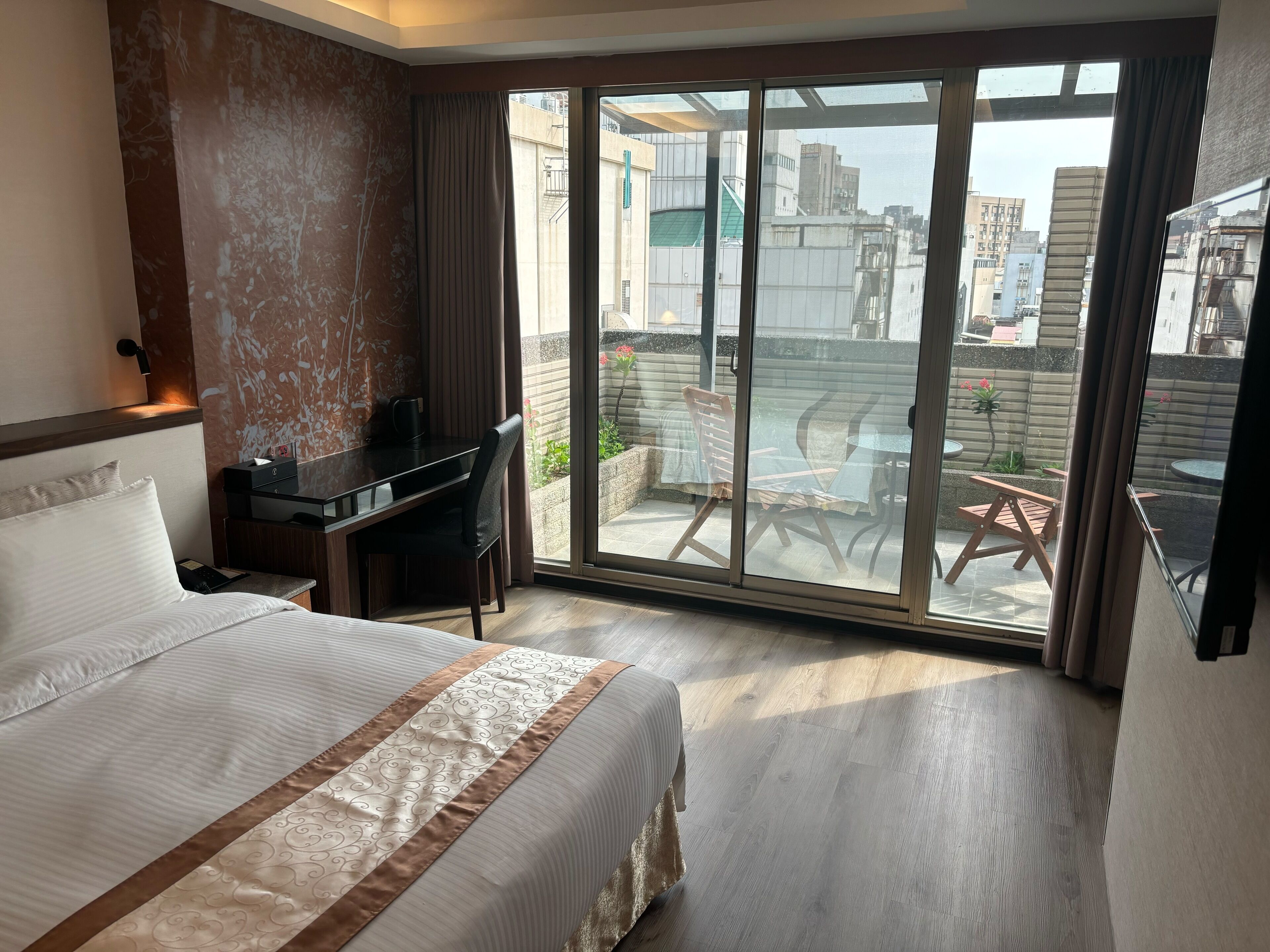 A hotel room with a bed, desk, and large sliding glass doors to an outdoor patio.