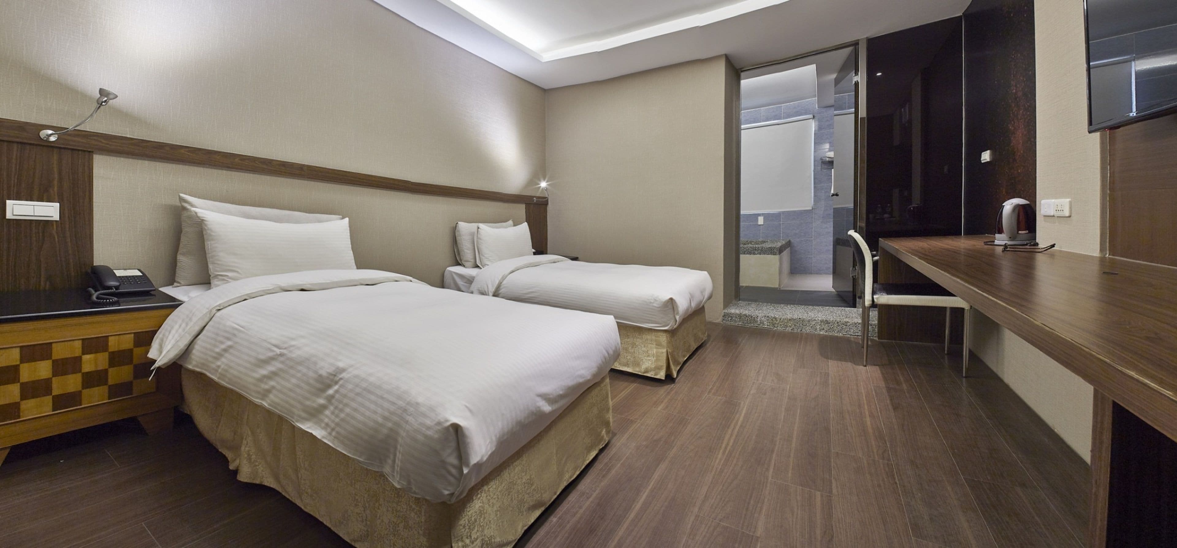 Une chambre d’hôtel avec deux lits, un bureau, un téléphone et un espace douche.
