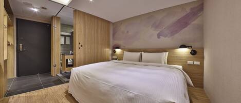 A modern bedroom with a large bed, wooden wardrobe, and a wall-mounted lamp.