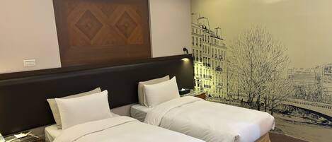 Une chambre d’hôtel avec deux lits simples, une tête de lit en bois, une fresque murale, une table de chevet et une lampe.