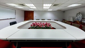 A conference room with a long table, chairs, a whiteboard, and a decorative sculpture.