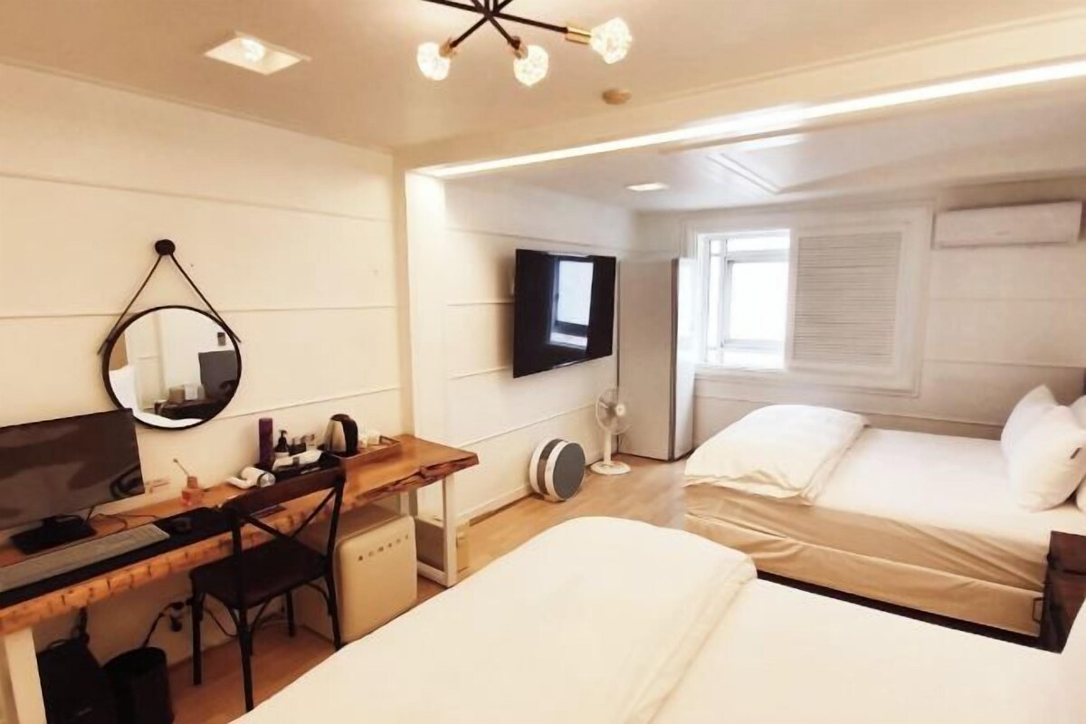 A hotel room with a desk, a bed, a TV, and a mirror.