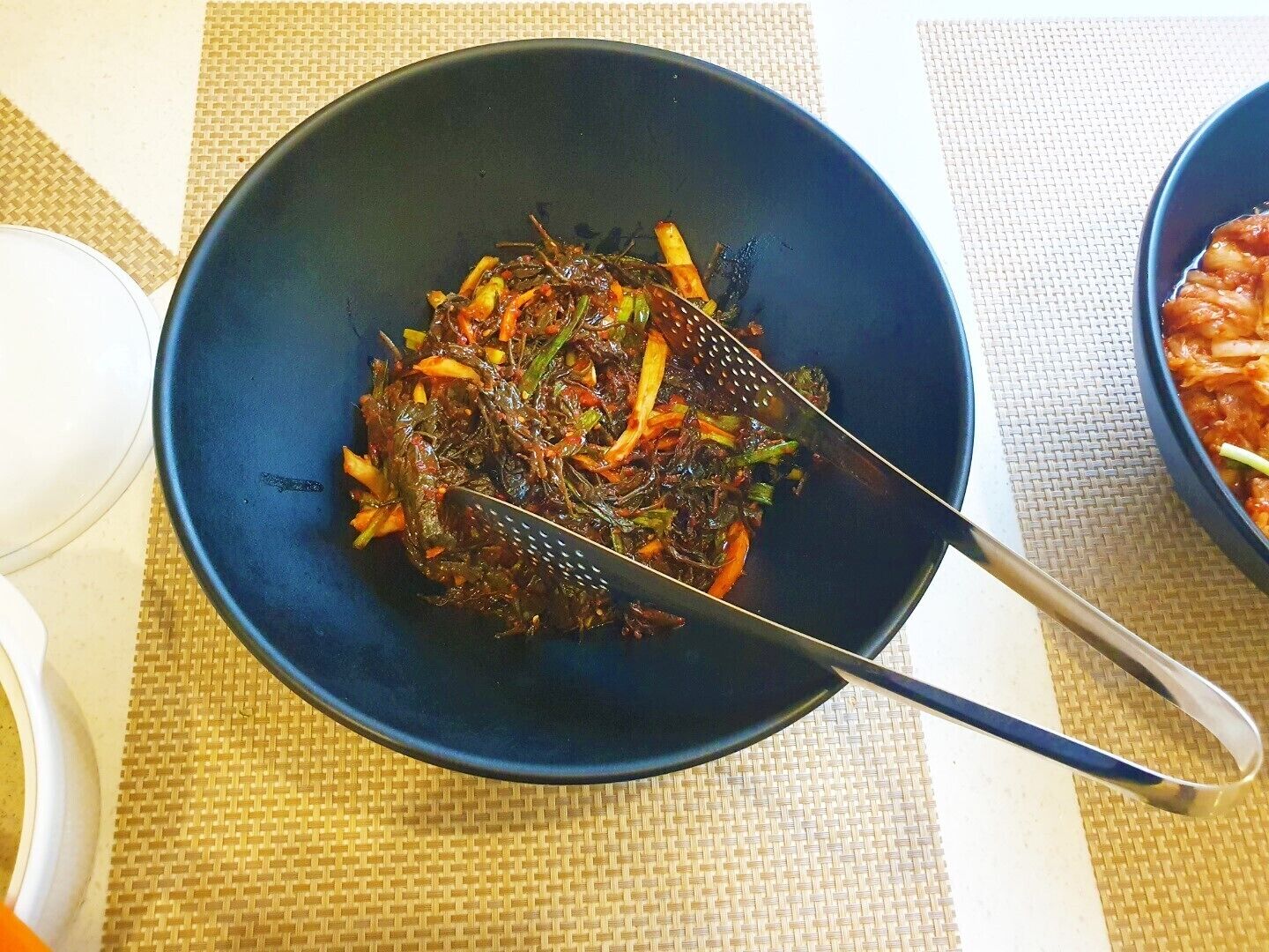 A bowl of stir-fried vegetables on a table with a woven placemat underneath.
