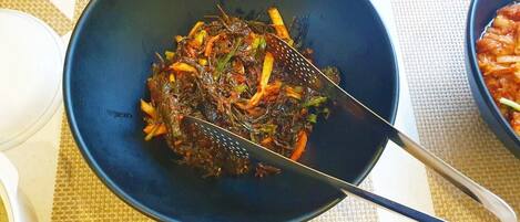 A bowl of stir-fried vegetables on a table with a woven placemat underneath.