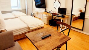 Ein modernes Hotelzimmer mit Bett, Schreibtisch, Stuhl, Fernseher, Spiegel und Deckenleuchte.
