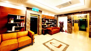 Eine Lobby mit einer Couch, Bücherregalen, einem Chandelier und einem Aufzug.