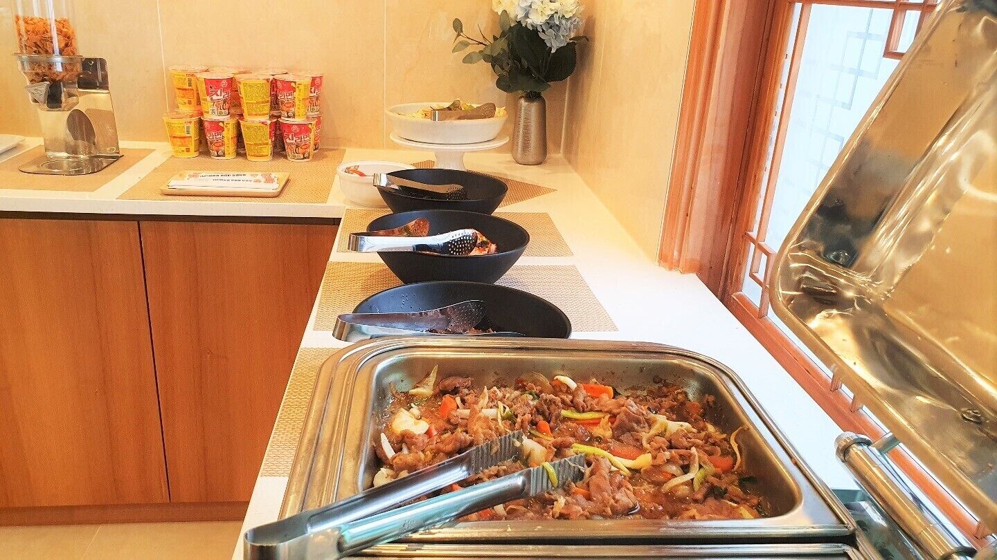Ein reichhaltiges Buffet mit verschiedenen Speisen, darunter ein Fleischgericht, Schüsseln und Beilagen.