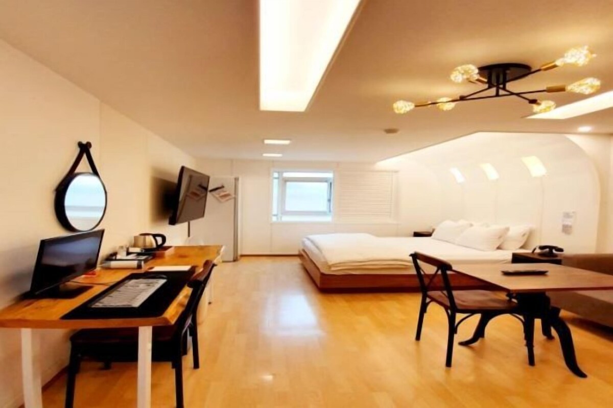 A modern room with a wooden desk, a bed, and a TV.