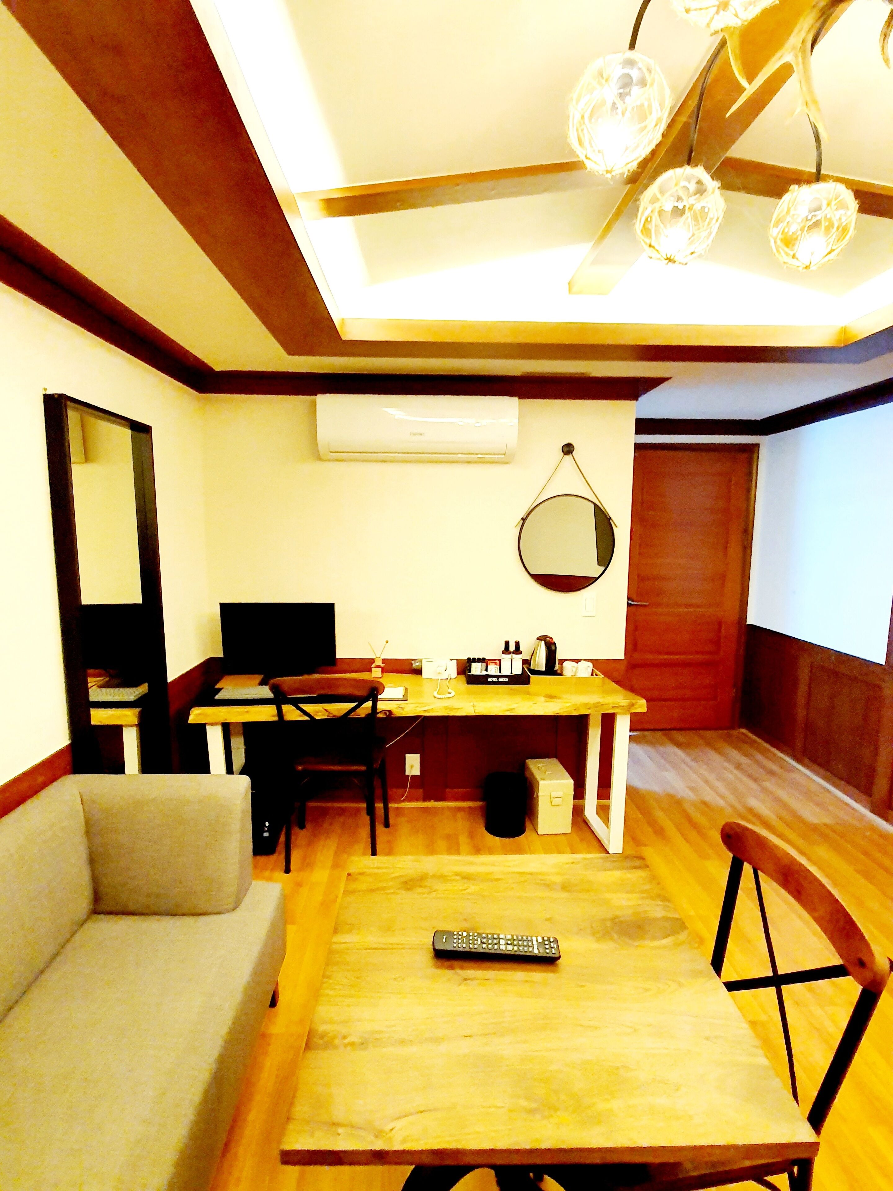 Un espacio habitable pequeño con sofá, mesa de comedor, kitchenette y ventilador de techo.