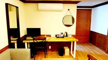 Un espacio habitable pequeño con sofá, mesa de comedor, kitchenette y ventilador de techo.