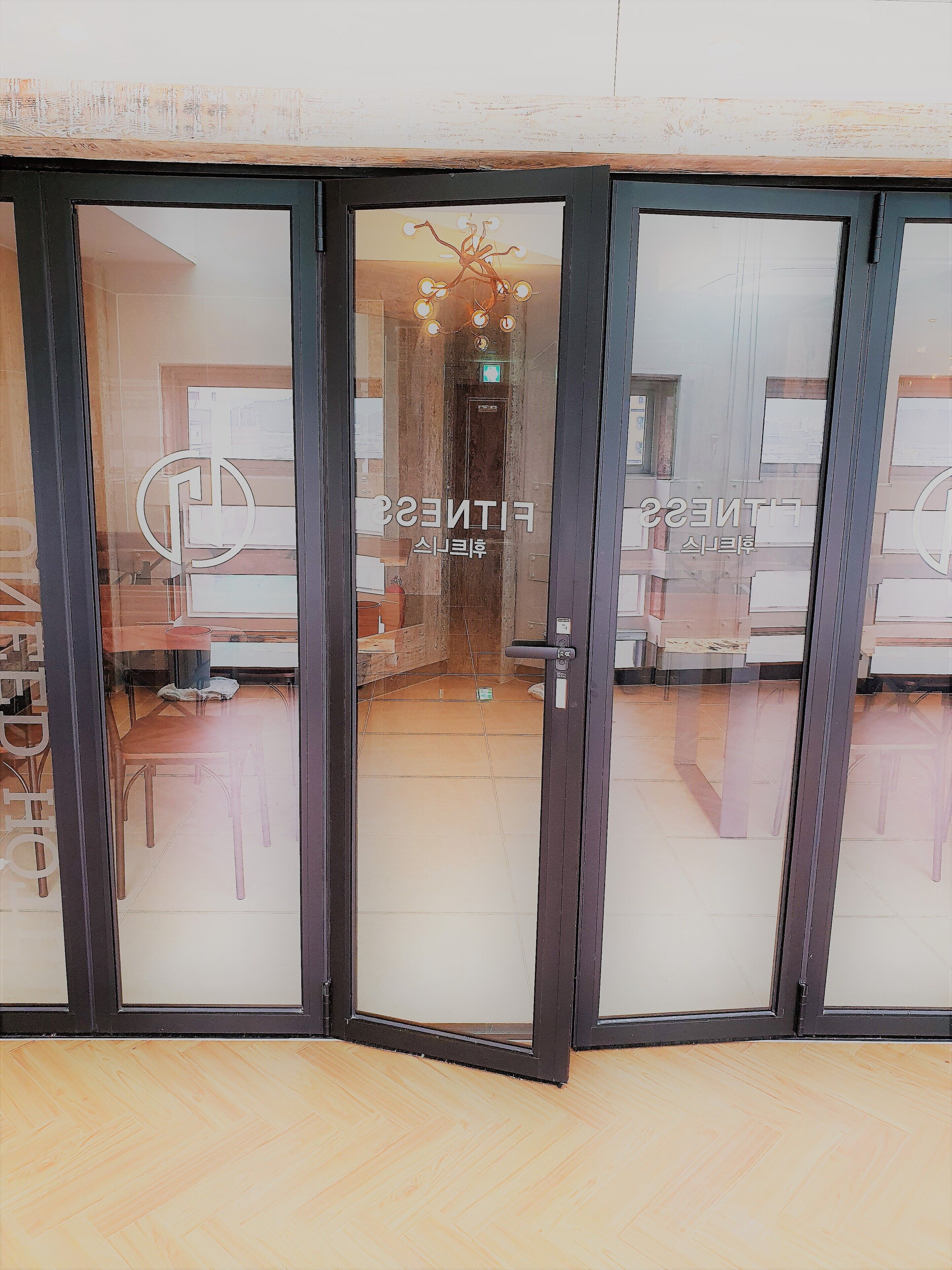 A hotel entrance with glass doors, a reception desk, and a chandelier.