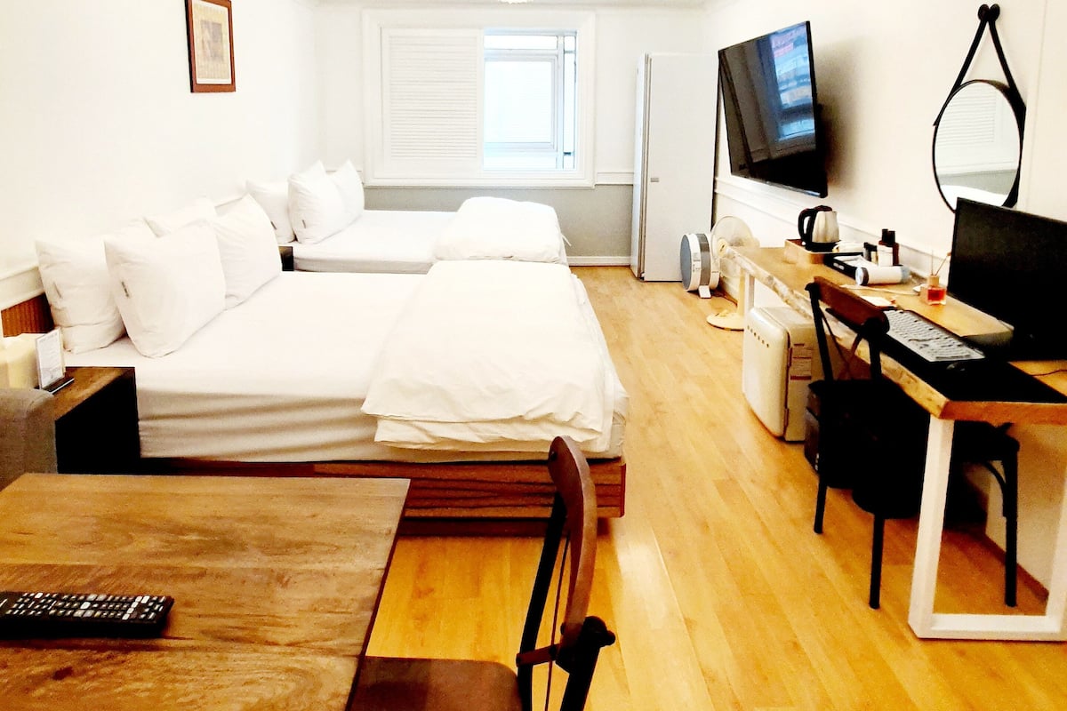 Habitación de hotel con dos camas, un escritorio, una silla, un televisor y una ventana.