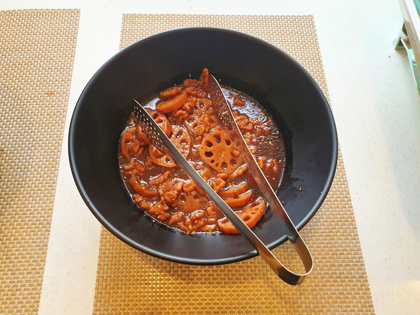A black bowl on a woven mat.