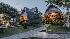 A resort with thatched-roof cottages, a paved walkway, and lush greenery. - Dream Beach Huts (Lembongan Island)