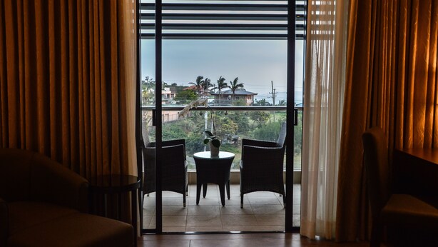 Una habitación con vistas a través de una ventana, que incluye una mesa con sillas y una planta en maceta.