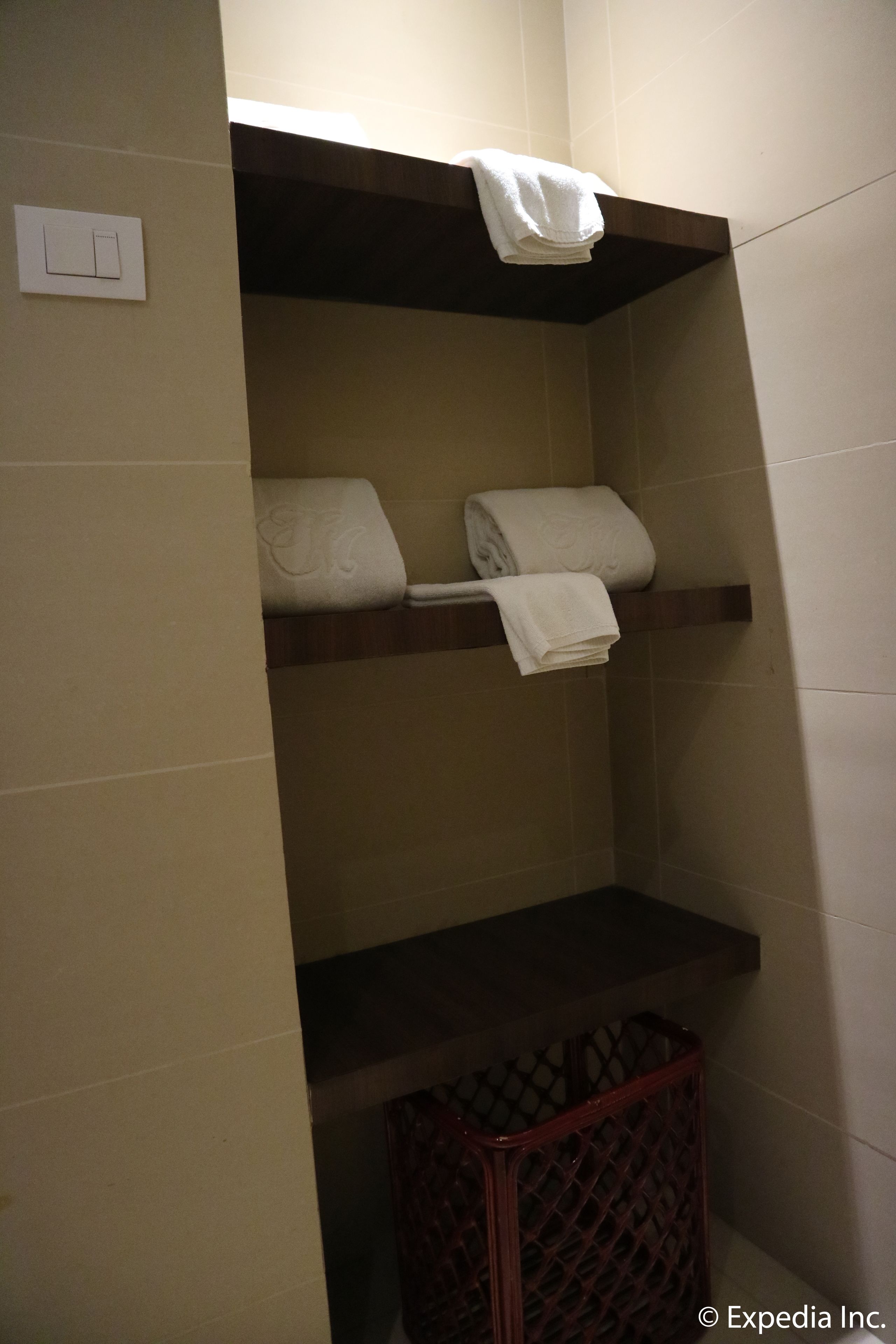 A bathroom with a towel rack, a trash bin, and a light switch.