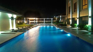 Una piscina con sillas de descanso y un edificio al fondo.