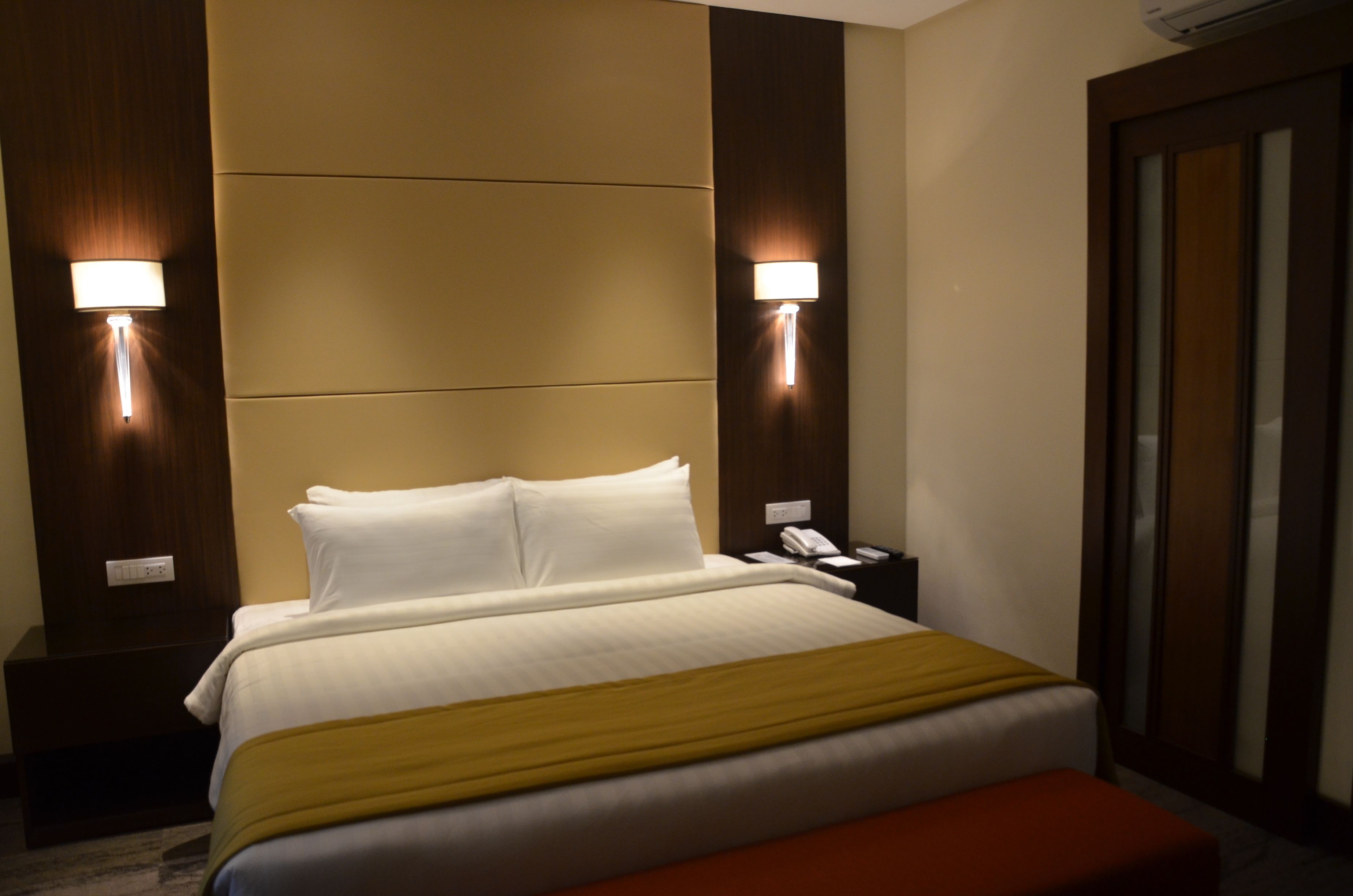 Une chambre d’hôtel avec un grand lit, deux lampes de chevet, un téléphone et une porte coulissante.